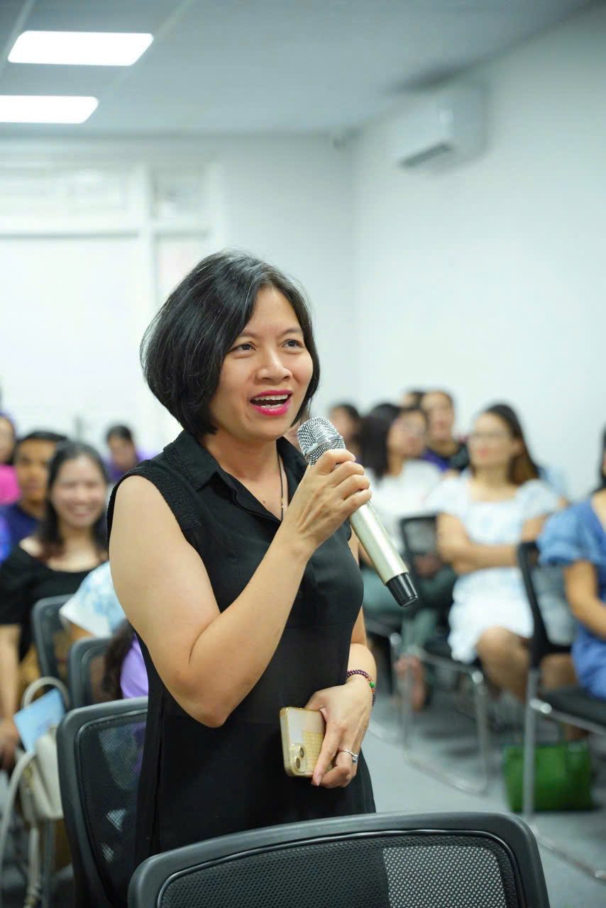 Chị Minh Hằng cầm micro đứng lên trao đổi giữa một buổi chia sẻ nghề đông người, đúng tinh thần học từ người đi trước mà chị theo từ ngày bắt đầu lại.
