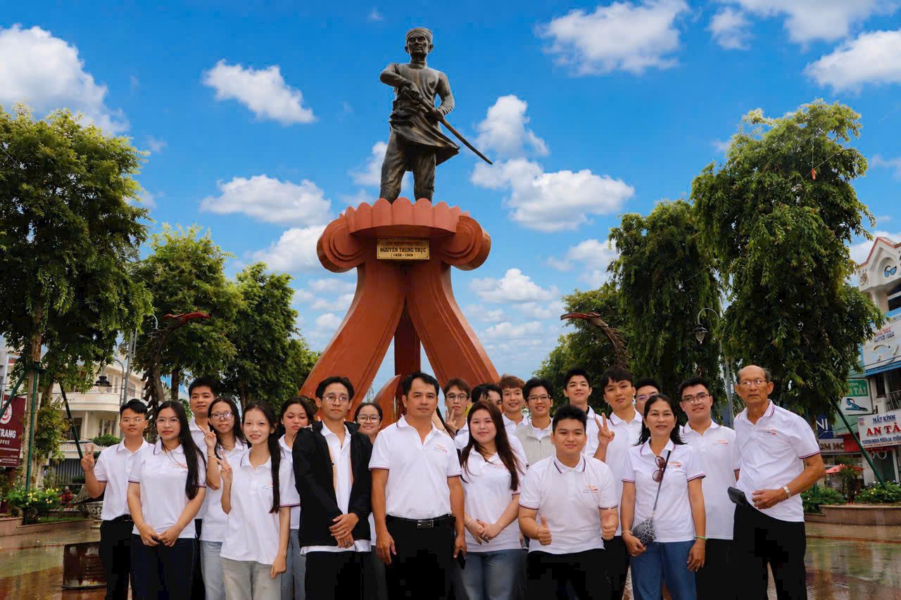 Anh Phạm Chí Hiếu cùng các bạn trẻ Việt Chí trong đồng phục trắng bên tượng đài Nguyễn Trung Trực ở Rạch Giá, những người đang chuẩn bị cho hành trình học nghề ở Đức.