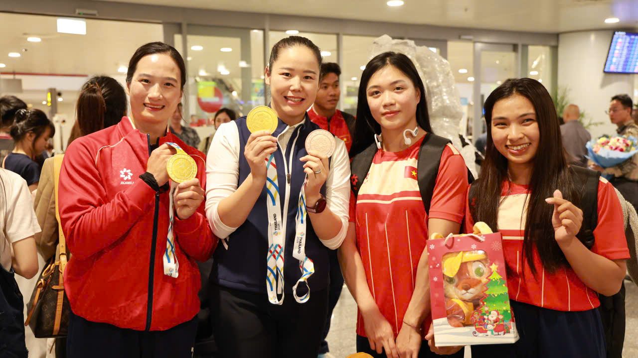 Chị Dương Thị Mai (giữa) cùng các nữ vận động viên rạng rỡ khoe những tấm huy chương trong ngày trở về ở sân bay, phần thưởng của bao lần rèn giũa mà chị vẫn nhắc các tay chèo của mình.