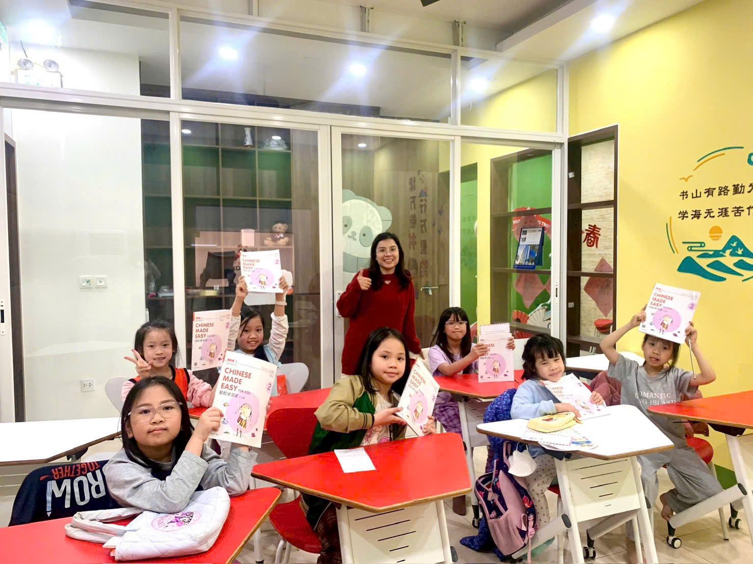 Một lớp thiếu nhi ở BAOBAOXUE giơ cao cuốn giáo trình tiếng Trung, trên tường là câu thơ khuyên chăm học, đúng tinh thần "học thật nhiều" chị Lan Anh muốn trao lại.