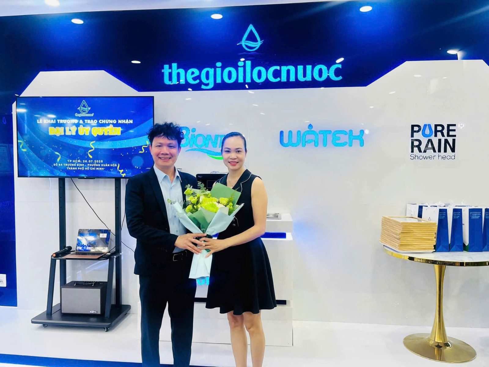 Chị Vân Anh tại lễ khai trương và trao chứng nhận đại lý ủy quyền của Thegioilocnuoc ở TP.HCM tháng 7/2025, giữa những dòng máy anh chị chọn để lan tỏa nước tốt.