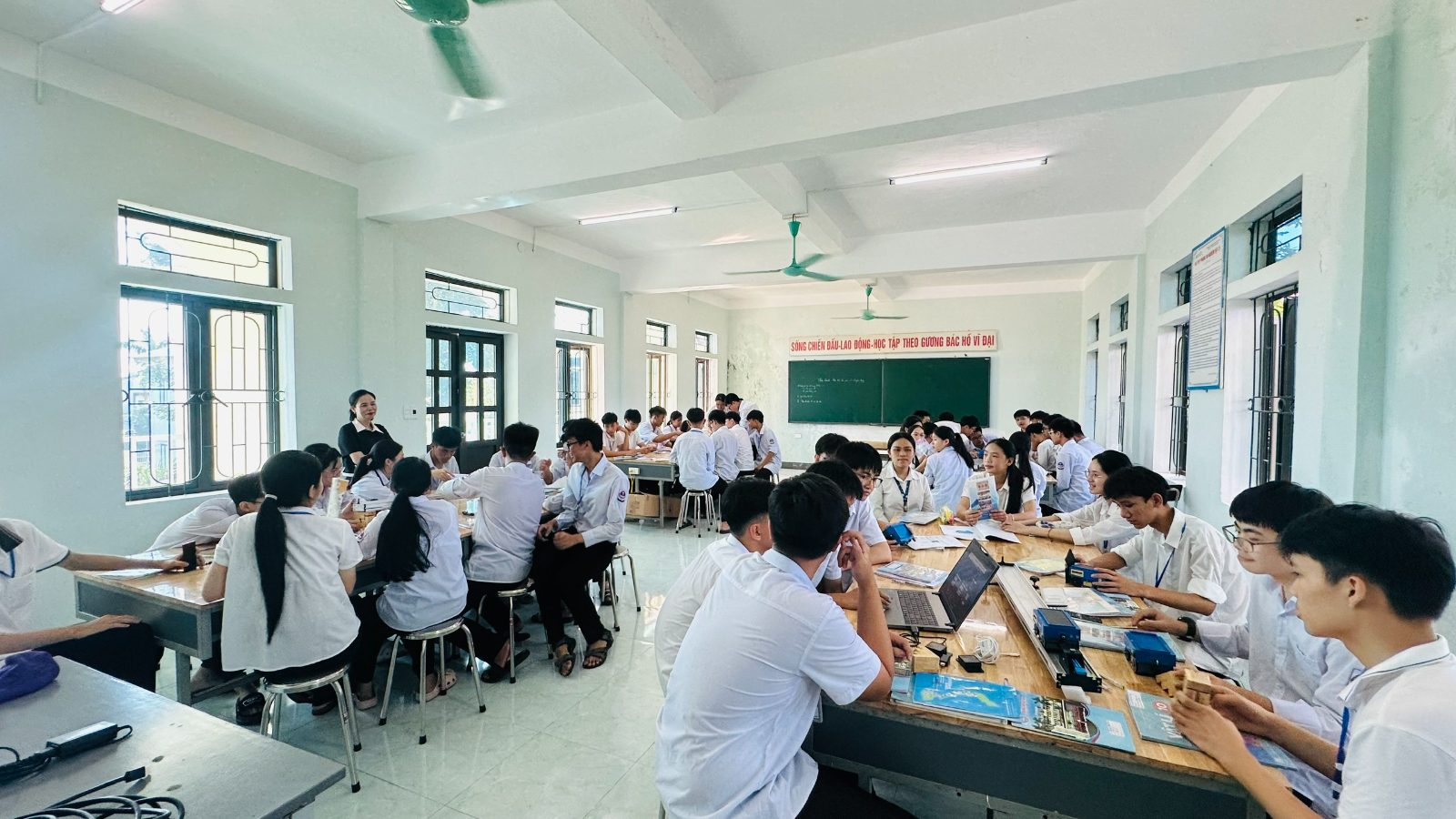 Học trò Trường THPT Kỳ Anh làm việc theo nhóm bên bộ thí nghiệm và máy tính trong phòng học Vật lý, kiểu tiết học các tổ cùng thi đua mà chị Trang hay dựng.