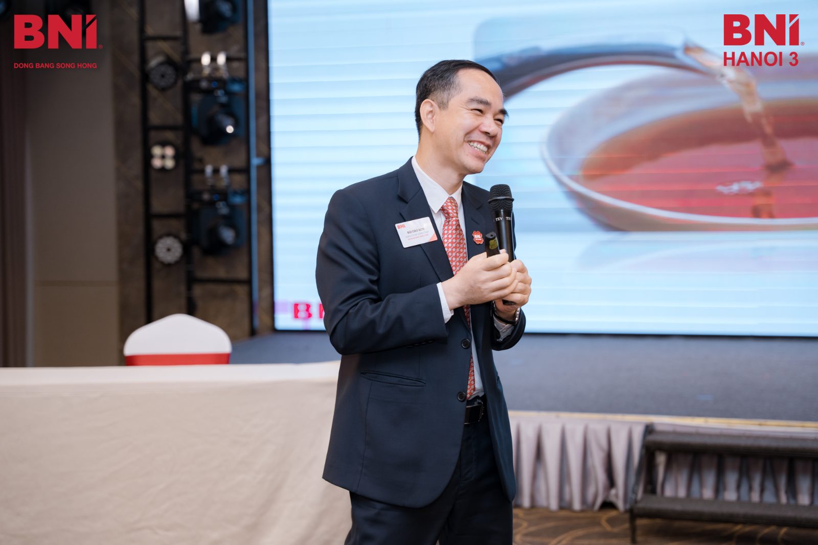 Anh Bùi Cao Sơn cầm micro trò chuyện cùng các chủ doanh nghiệp trong một buổi sinh hoạt của BNI Hà Nội 3, cộng đồng anh dẫn dắt ở vùng Đồng bằng sông Hồng.
