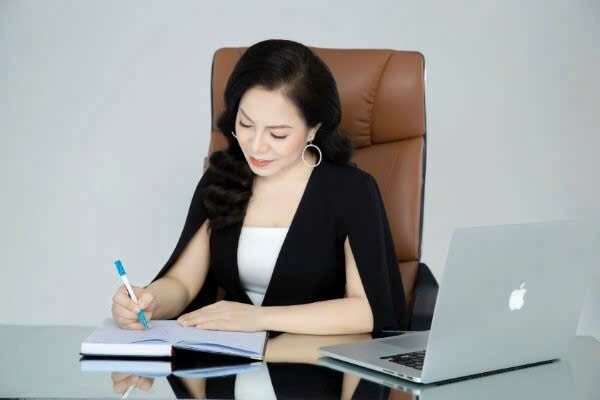 Chị Hòa ngồi ghi chép bên bàn làm việc, chiếc máy tính mở sẵn cạnh cuốn sổ, nơi chị đang tập đưa mười lăm năm nghề spa lên mạng.